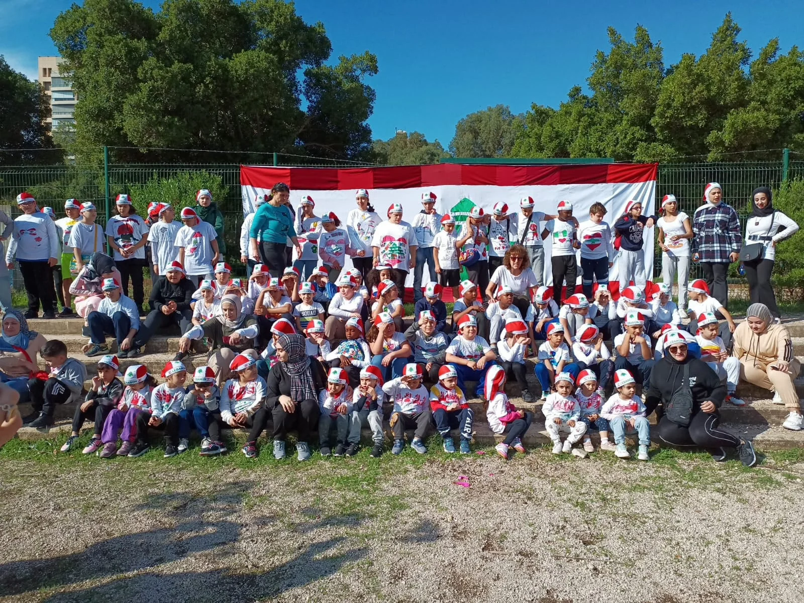 The Heritage College community gathered outdoors in front of a Lebanese flag