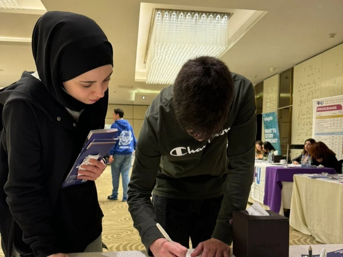 A student writing at a table with support from a representative